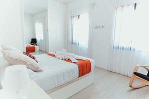 Ein modernes Hotelzimmer mit einem großen Bett, einem Sessel und einem Spiegel.