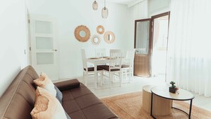 A modern living room with a brown sofa, a dining table with white chairs, and a round coffee table.