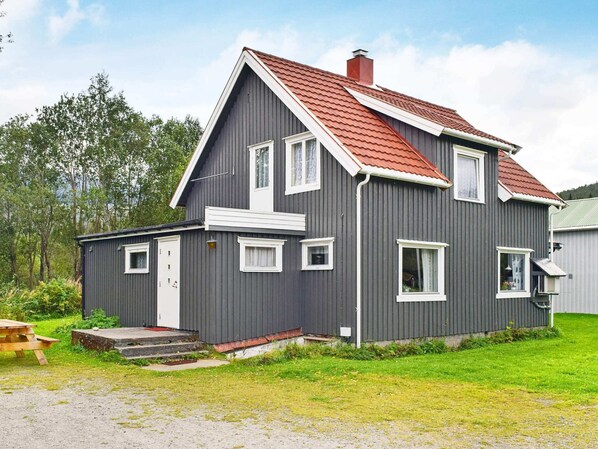 A two-story house with a red roof, grey siding, and white trim.