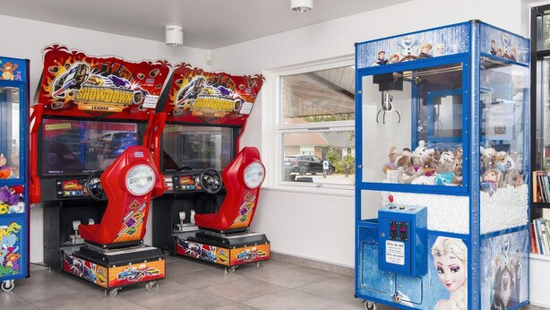 Deux bornes d’arcade, une machine à pinces et une fenêtre donnant sur la rue.