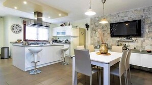 A modern kitchen with a central island, white cabinetry, and a dining area with a white table and chairs. - Belvilla by OYO Villa in Adeje (Adeje)