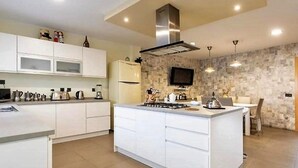 A modern kitchen with white cabinetry, a central island, a stove, and a microwave. - Belvilla by OYO Villa in Adeje (Adeje)
