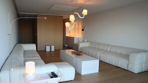 A modern living room with a white sofa set, a white coffee table, and a unique chandelier. - Romantic Coastal Escape (Nieuwpoort)