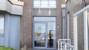 A building entrance with a glass door, a metal staircase, and a brick facade. - Romantic Coastal Escape (Nieuwpoort)