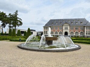 A historic building with a central fountain, surrounded by a paved courtyard and well-maintained hedges. - Modern Holiday Home in Maasmechelen With Sauna (Maasmechelen)