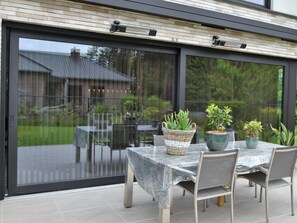 An outdoor patio with a table and chairs, a wicker basket, and potted plants. - Modern Holiday Home in Maasmechelen With Sauna (Maasmechelen)