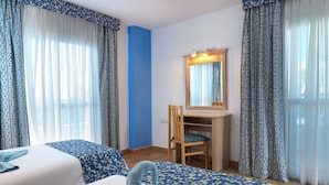 Une chambre d’hôtel avec deux lits, un bureau, une chaise et un miroir.