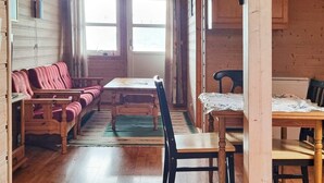 Una habitación acogedora con piso de madera, un sofá, una mesa y una silla.