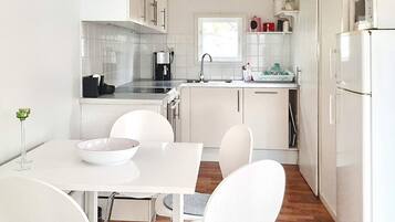 A modern kitchen with white cabinetry, a dining table with chairs, and a refrigerator.