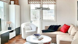 Un salon moderne avec un canapé blanc, un fauteuil blanc, une table basse ronde et un tapis blanc.