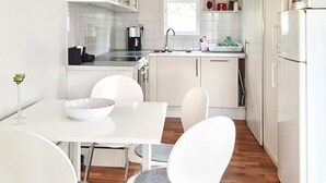 Une cuisine moderne avec des meubles blancs, une table à manger avec des chaises et un réfrigérateur.