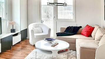 A modern living room with a white sofa, a white armchair, a round coffee table, and a white rug.