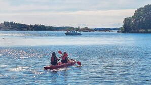 Une étendue d’eau calme sur laquelle navigue un petit bateau rouge, transportant deux personnes.