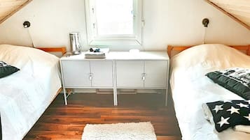 Ett studentrum med två sängar, ett skrivbord och ett fönster.