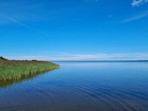 Un cuerpo de agua tranquilo con un cielo despejado y una orilla distante.