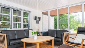 Una sala de estar moderna con un sofá, sillas, una mesa y una planta en maceta.