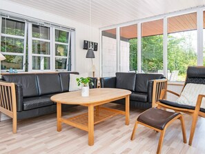 Un salon moderne avec un canapé, des fauteuils, une table et une plante en pot.