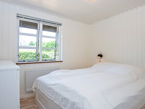 Una habitación con una cama, un radiador y una ventana con persianas.