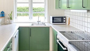 A kitchen with green cabinets, a microwave, and a dish drying rack. - 6 Person Holiday Home in Ulfborg (Ulfborg)