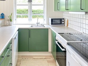 A kitchen with green cabinets, a microwave, and a dish drying rack. - 6 Person Holiday Home in Ulfborg (Ulfborg)