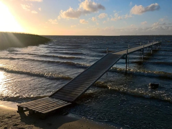 A wooden pier extending into the ocean with waves crashing at its end.