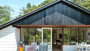 Una casa moderna con porche cubierto, ventanas amplias y mobiliario de exterior.