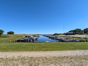Een jachthaven met boten, grasvelden en een heldere blauwe lucht.