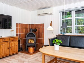 Una habitación acogedora con chimenea, un aparador de madera, una mesa, un sofá y una ventana con vistas a la vegetación.