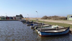 A row of boats docked at a marina with small buildings in the background. - 6 Person Holiday Home in Ulfborg (Ulfborg)