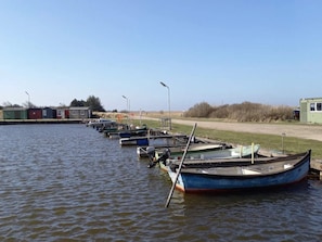 A row of boats docked at a marina with small buildings in the background. - 6 Person Holiday Home in Ulfborg (Ulfborg)