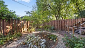 A garden with a wooden fence, gravel path, and various plants.