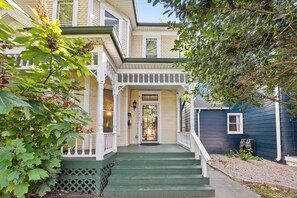 A two-story house with a porch, a front door, and a small window.