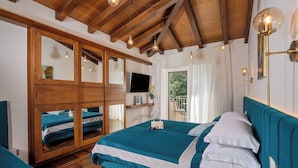 Une chambre avec un grand lit, une armoire, une télévision et une fenêtre avec des rideaux.