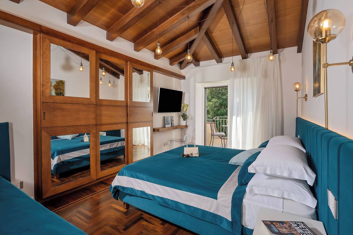 Un dormitorio con una cama grande, un armario, un televisor y una ventana con cortinas.