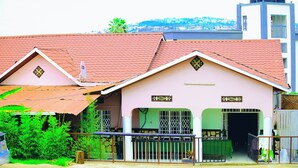 Une maison à deux étages, avec un toit recouvert de tuiles rouges, un balcon doté d’une balustrade en métal et une porte verte.