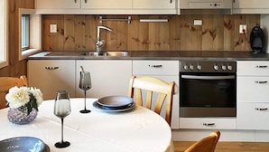 Una cocina moderna con paneles de madera, electrodomésticos de acero inoxidable y un comedor con mesa dispuesta para dos.