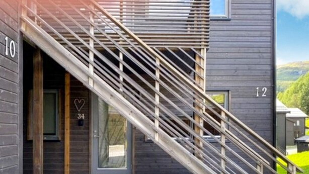 Un edificio moderno con una escalera de madera que conduce a una puerta marcada con el número 34.