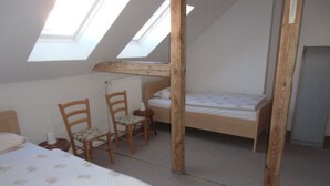 A dormitory room with two beds, wooden chairs, a radiator, and skylights. - Bille Comfortable Holiday Residence (Luckenwalde)