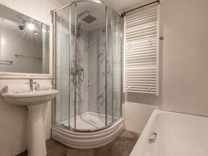 Une salle de bain moderne avec une douche à parois de verre, un lavabo sur colonne et une baignoire.