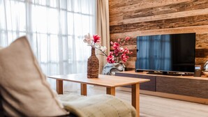 Ett modernt vardagsrum med en väggpanel av trä, en platt-TV, ett soffbord i trä och en soffa med en kudde.
