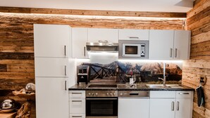 Ett modernt kök med vita skåp, vitvaror i rostfritt stål och en träpanel på väggen.