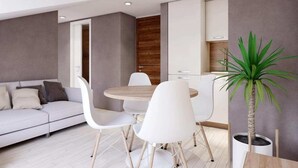 Een moderne woonkamer met een bank, eettafel, stoelen en een potplant.