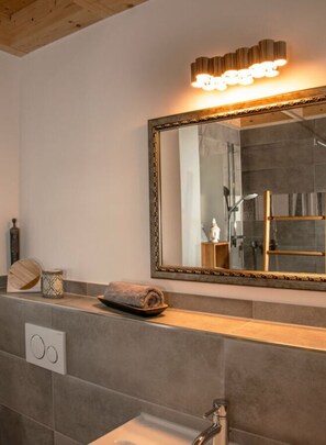 A bathroom with a large mirror, a towel on the counter, and a shower area.