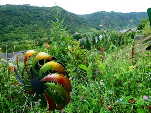 A garden with a metal sculpture amidst greenery and hills in the background. - Emerald - Holiday Home for (Burgen)