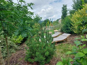A garden with wooden benches, a climbing frame, and various plants. - Emerald - Holiday Home for (Burgen)