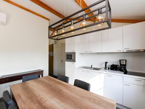 Una cocina moderna con armarios blancos, una mesa de comedor de madera y una lámpara colgante.