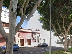 A building with a red facade, arched doorways, and a sign that reads "FARMACIA". - Apartment in Puerto del Rosario Near Playa Chica (Puerto del Rosario)