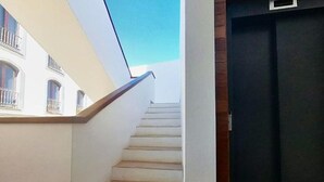 A staircase leading to a dark door, with a white wall and a window on the left. - Apartment in Puerto del Rosario Near Playa Chica (Puerto del Rosario)