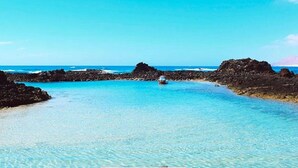 A wooden pier leading into clear turquoise waters with rocky formations on either side. - Apartment in Puerto del Rosario Near Playa Chica (Puerto del Rosario)