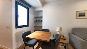 A compact living space with a dining table, two chairs, a sofa, a lamp, and a window. - Apartment in Puerto del Rosario Near Playa Chica (Puerto del Rosario)